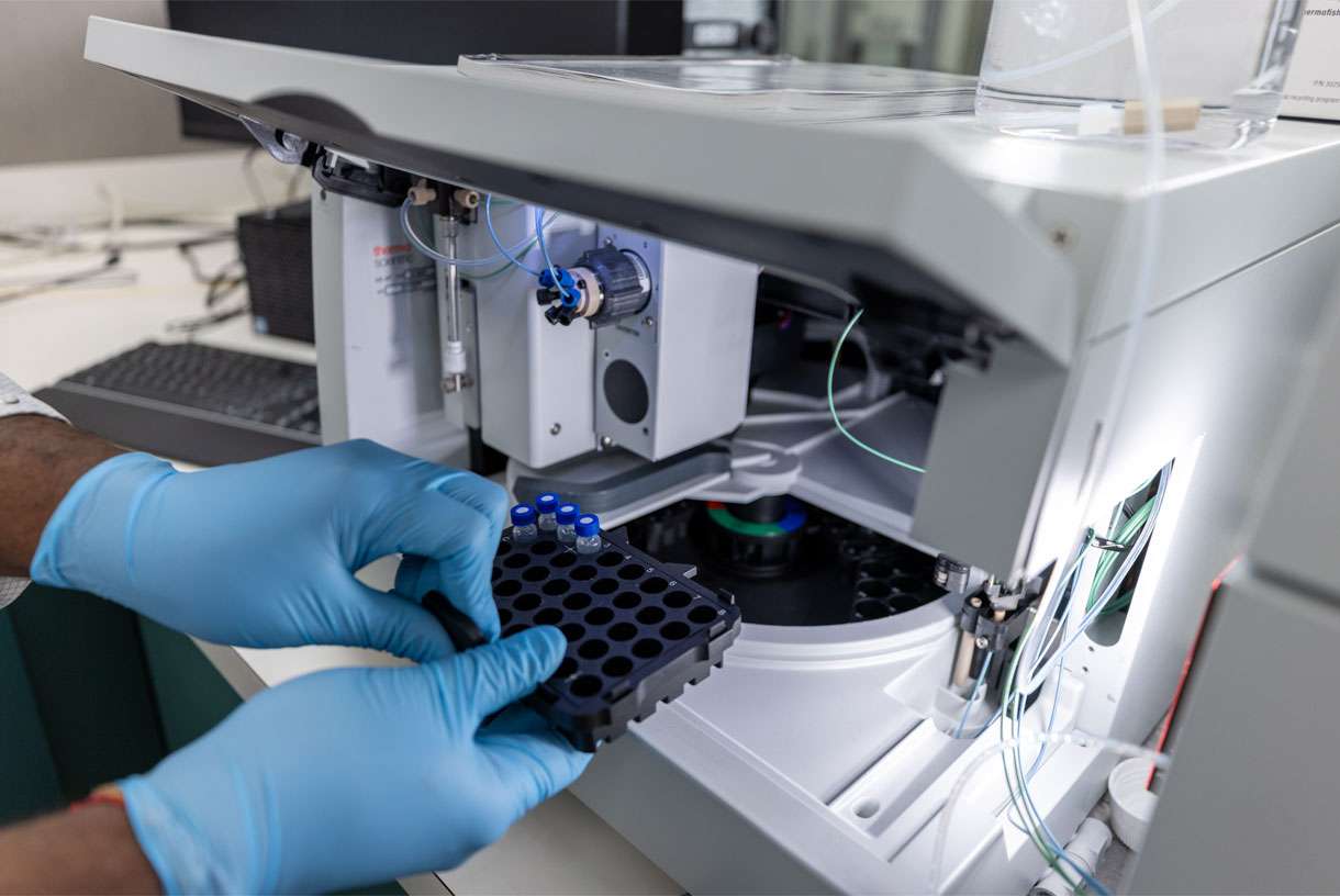 A Pii scientist inserting vials into testing equipment.